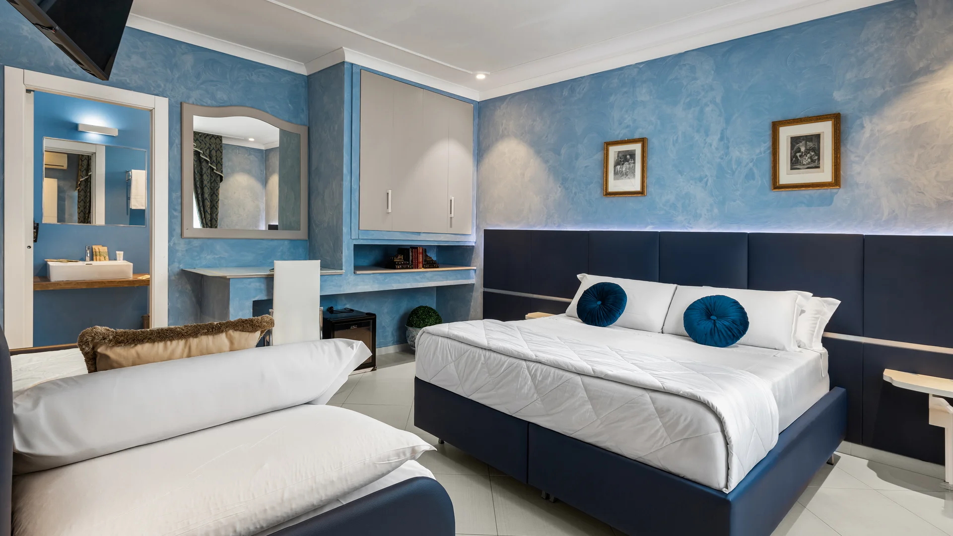Camera d'hotel con letto matrimoniale, divano e pareti azzurre