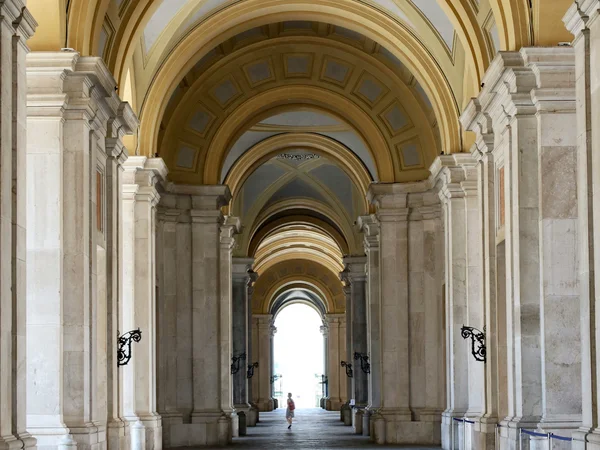 Galleria con archi e colonne in marmo con soffitto decorato e persona sullo sfondo