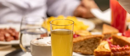 Due persone che si passano una ciotola di frutta fresca a una tavola con pane e succo