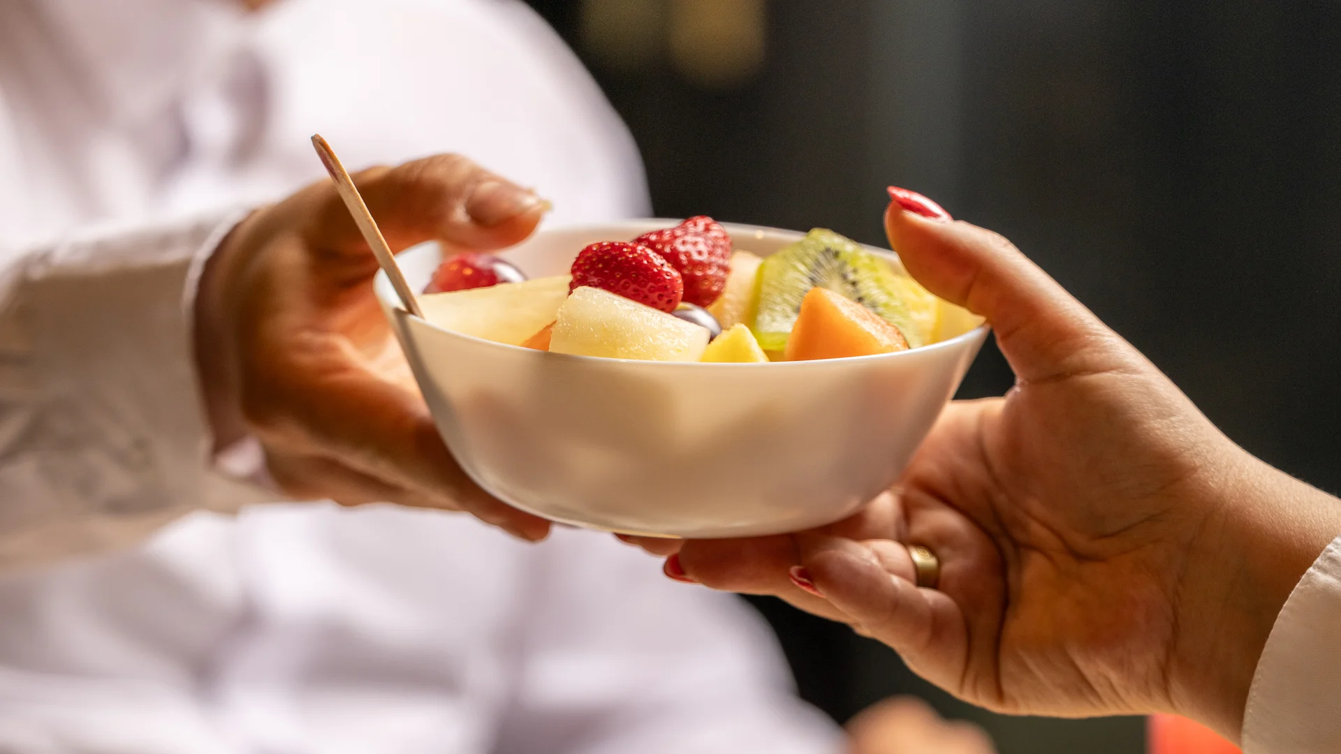 B&b a Caserta vicino alla Reggia · La colazione reale Due persone che si passano una ciotola di frutta fresca a una tavola con pane e succo