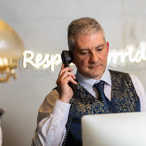 Receptionist in gilet elegante risponde al telefono davanti al computer