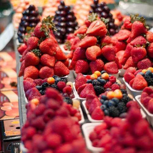 Hotel Regina Caserta · Sapori di Campania Cestini di frutti di bosco freschi con fragole, more e uva esposti su un banco