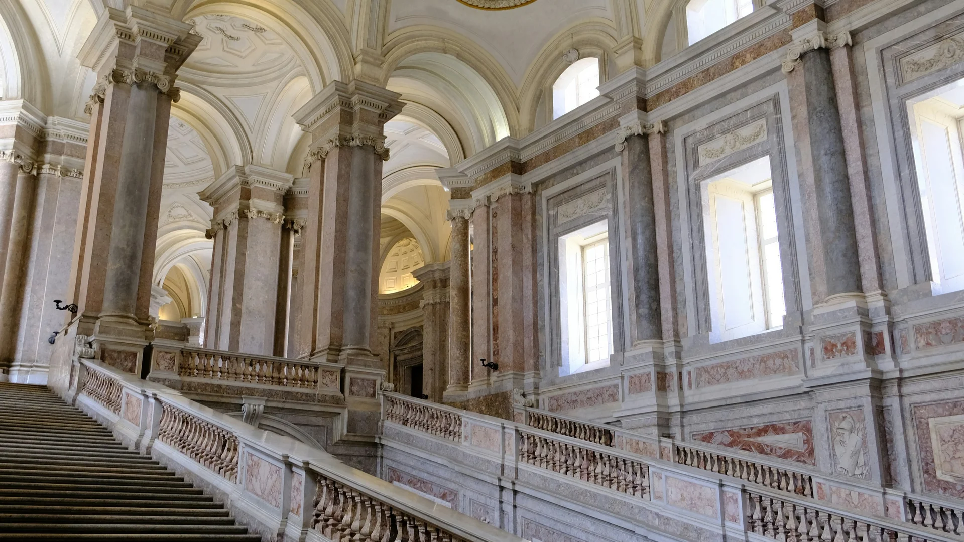 Grande scalinata in marmo con balaustre ornate e soffitti affrescati in edificio storico