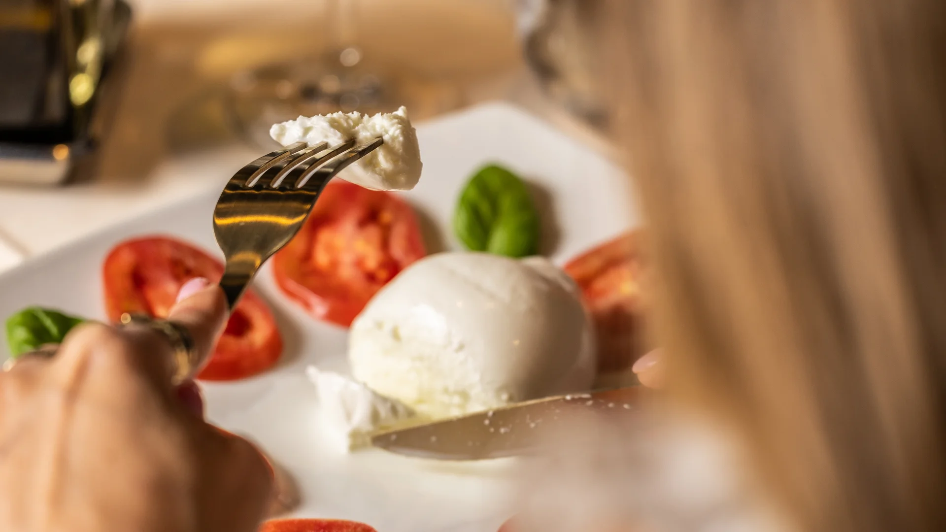 Donna che mangia insalata caprese con mozzarella, pomodori e basilico