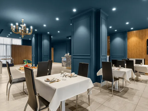Hotel Regina Caserta · Sapori di Campania Sala da pranzo elegante con tavoli apparecchiati e pareti blu scuro