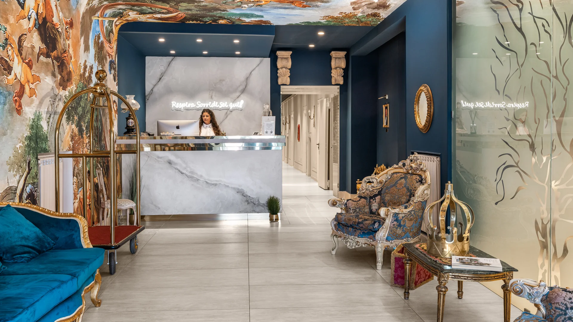 Hotel Regina · Il tuo hotel per coppie a Caserta Reception di hotel con decorazioni barocche, divani blu e soffitto affrescato