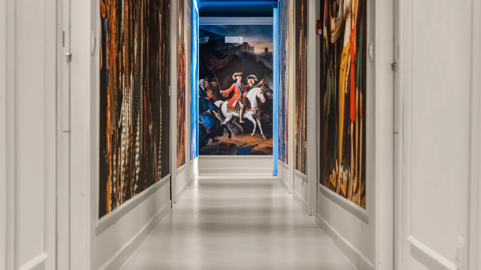 Corridoio con pareti decorate da grandi dipinti storici e quadro di uomo a cavallo