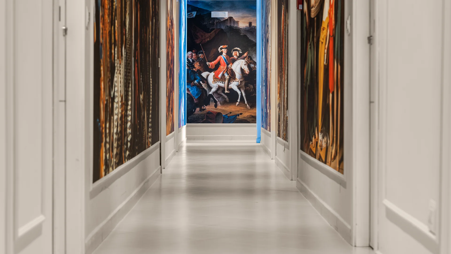 Corridoio con pareti decorate da grandi dipinti storici e quadro di uomo a cavallo