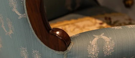 Primo piano di una poltrona vintage con tappezzeria blu floreale e bracciolo in legno