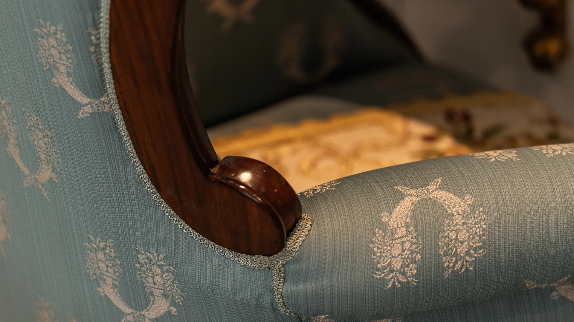 Primo piano di una poltrona vintage con tappezzeria blu floreale e bracciolo in legno