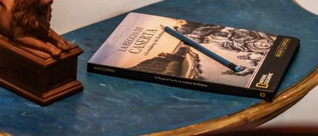 Tavolino blu con libro, matita e statuetta di leone, sedia azzurra decorata