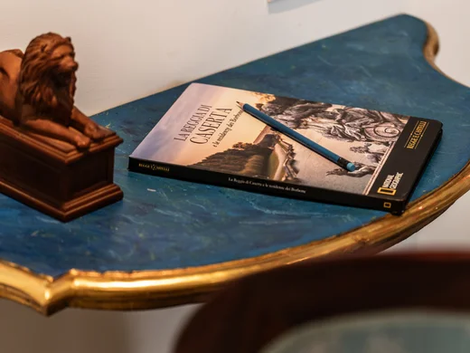 Tavolino blu con libro, matita e statuetta di leone, sedia azzurra decorata
