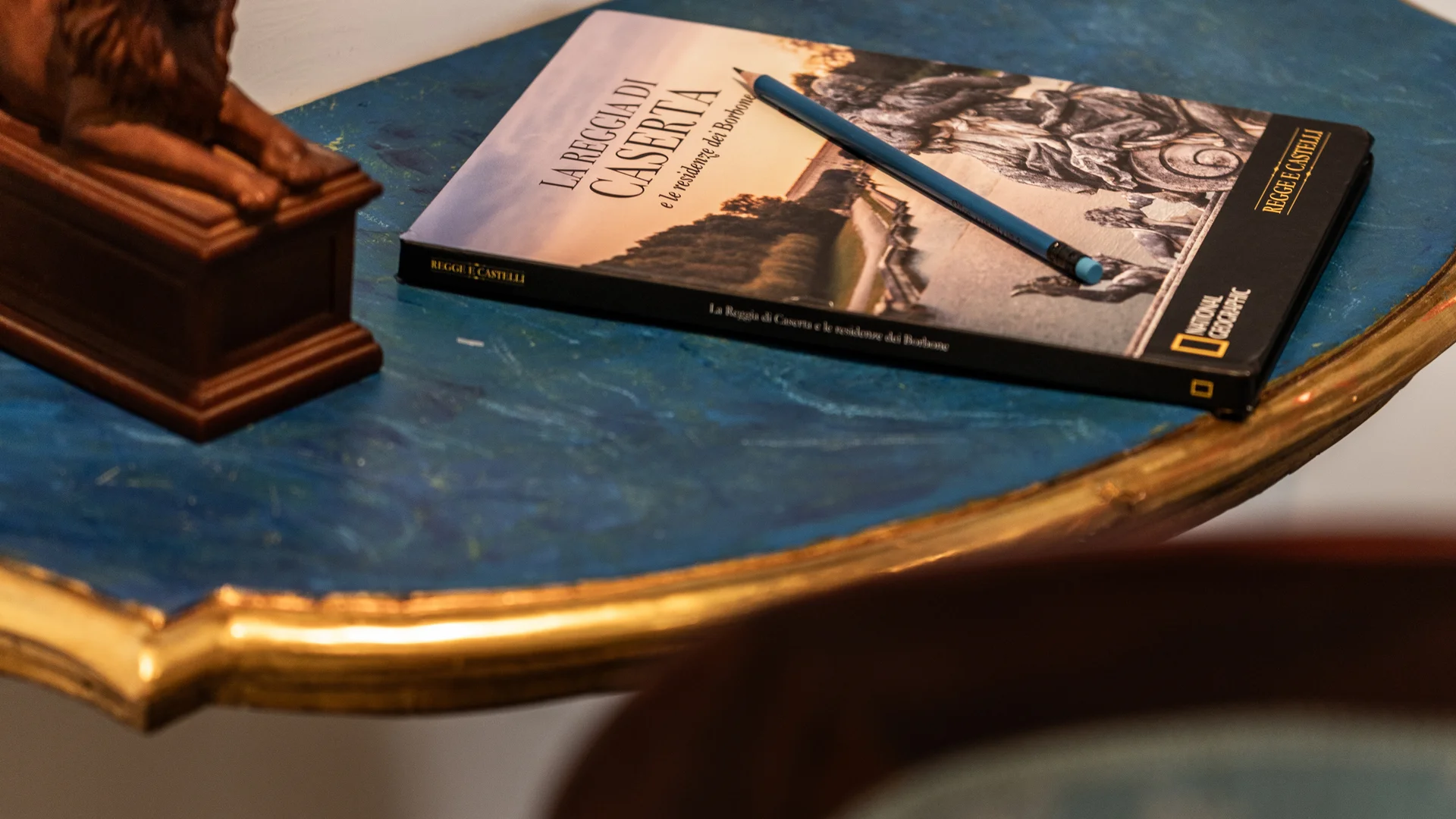 Tavolino blu con libro, matita e statuetta di leone, sedia azzurra decorata