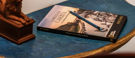 Tavolino blu con libro, matita e statuetta di leone, sedia azzurra decorata