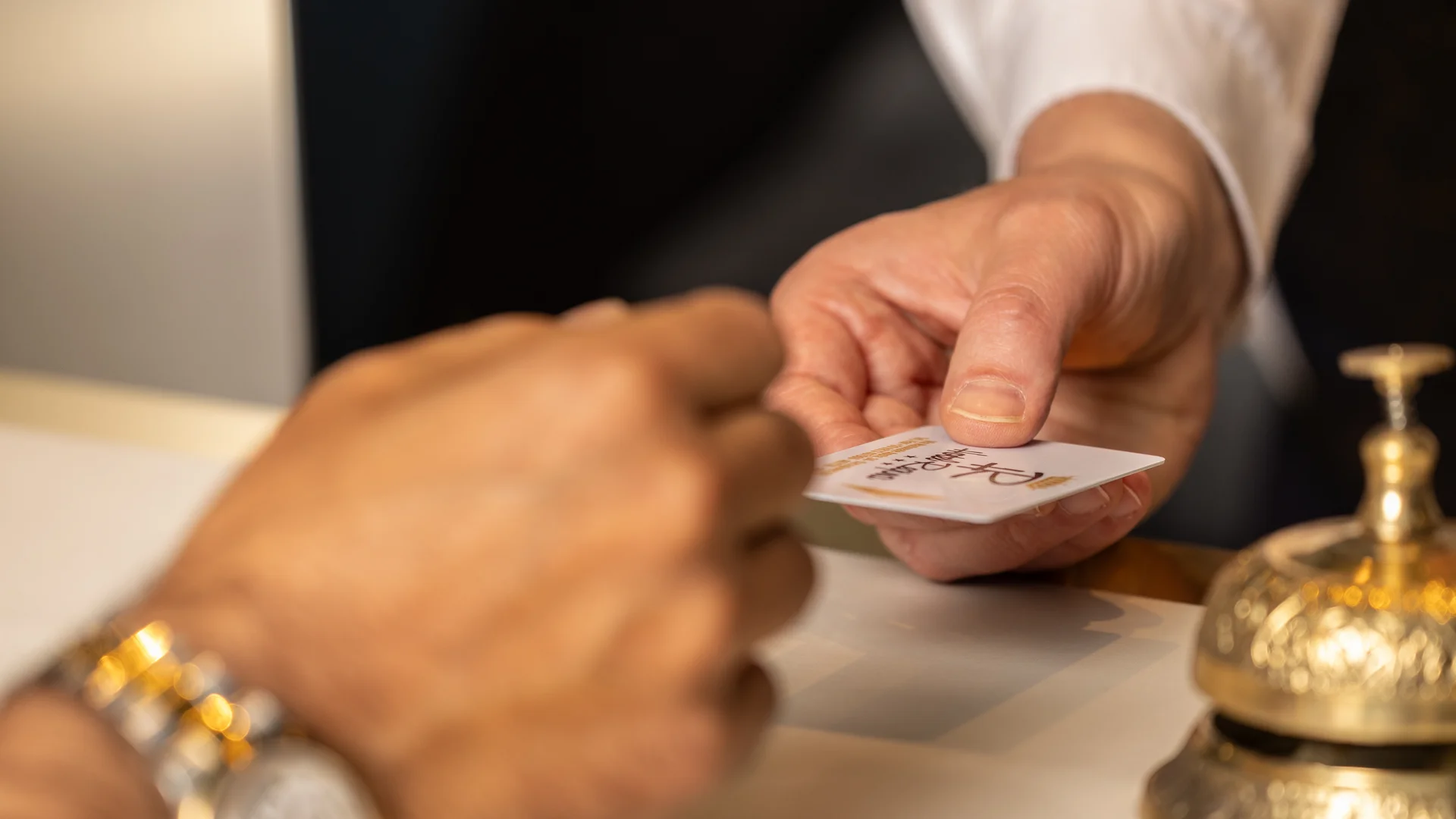 Scambio di una chiave o tessera alla reception di un hotel con campanello dorato