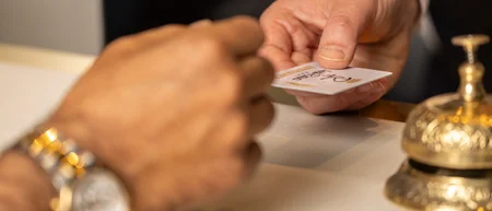 Scambio di una chiave o tessera alla reception di un hotel con campanello dorato