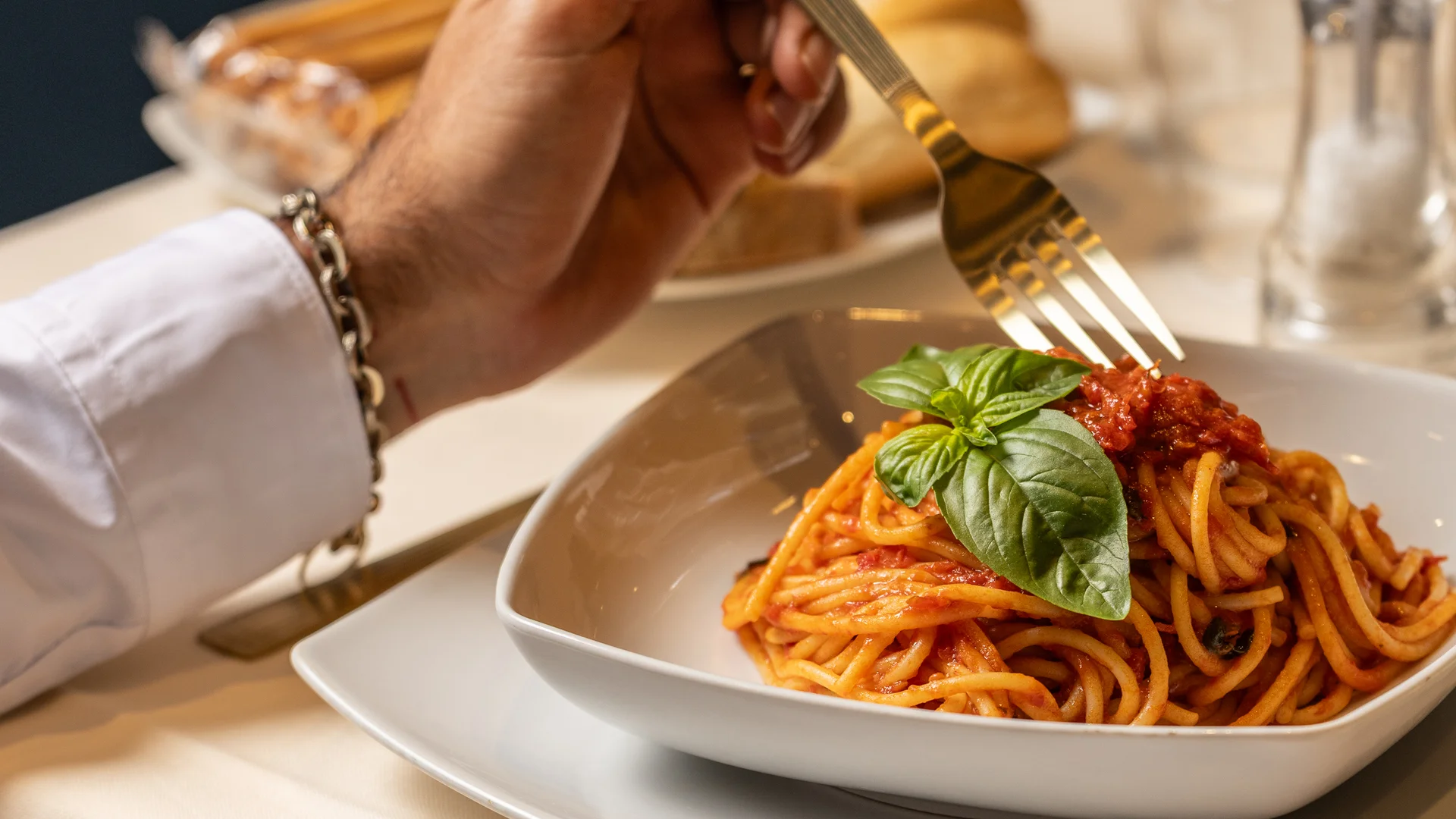 Hotel Regina Caserta · Sapori di Campania Persona che mangia spaghetti al pomodoro con foglia di basilico in piatto bianco