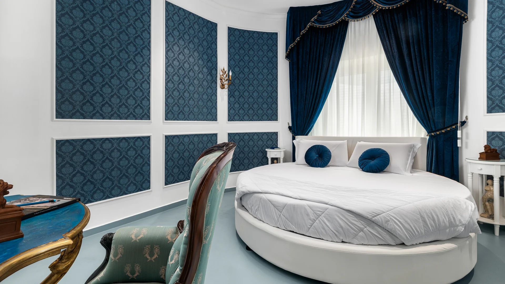 Camera da letto elegante con letto rotondo bianco e tende blu scuro