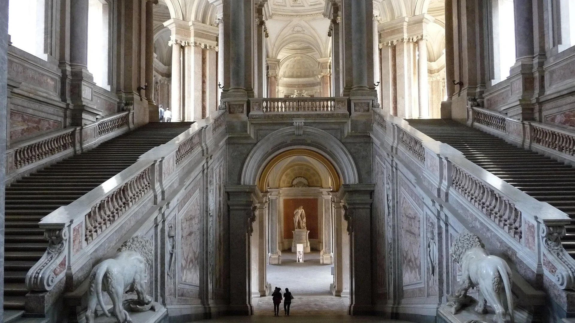 Interno di un grande palazzo con due scale simmetriche e statue di leoni in marmo