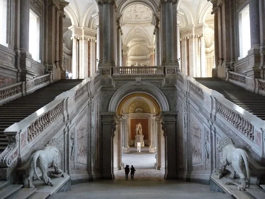Interno di un grande palazzo con due scale simmetriche e statue di leoni in marmo