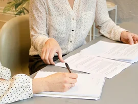 Due donne con camicie a pois che esaminano documenti e prendono appunti a un tavolo