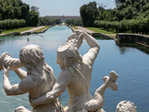 Hotel Regina: alla scoperta del Casertano Statua di due figure mitologiche vicino a un lungo canale d'acqua con giardini e palazzo sullo sfondo